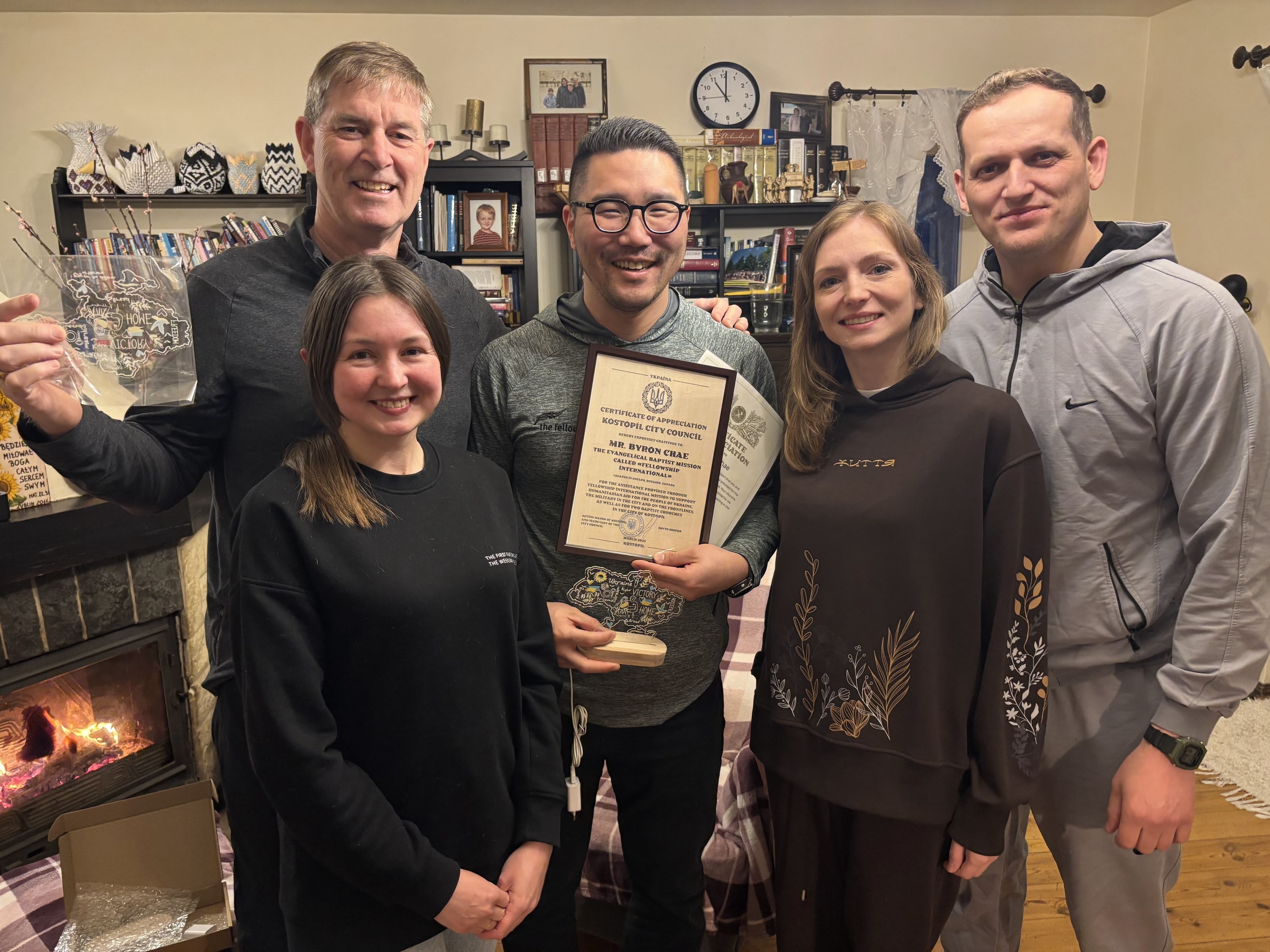 Byron Chae holding a Certificate of Appreciation from Kostopil City Council alongside local partners in Poland